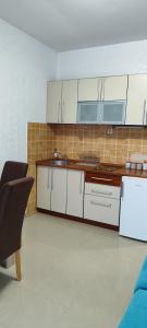 a kitchen with white cabinets and a tile wall at Sea and Sunshine in Tivat