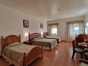 um quarto de hotel com duas camas e uma mesa em Hotel Quinta dos Cedros em Celorico da Beira