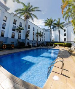 a swimming pool in front of a building with palm trees at Hampton By Hilton San Jose Airport Costa Rica in Alajuela City