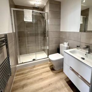 uma casa de banho com um chuveiro, um WC e um lavatório. em Luxury 1 Bedroom Apartment in Old Trafford em Manchester