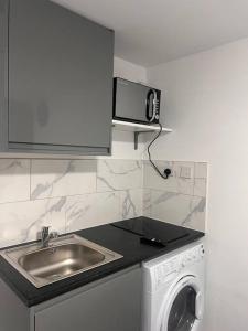 a kitchen with a sink and a washing machine at Cosy and warm studio apartment in Bexleyheath in Belvedere