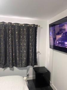a bedroom with a bed and a flat screen tv at Cosy and warm studio apartment in Bexleyheath in Belvedere
