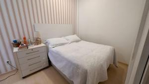 een slaapkamer met een wit bed en een nachtkastje bij Praia de Ipanema in Rio de Janeiro