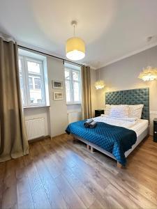 a bedroom with a bed with a blue comforter and two windows at Starovka Apartament in Elblag