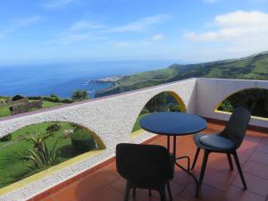 einen Tisch und zwei Stühle auf einem Balkon mit Meerblick in der Unterkunft Villa Cedros in Santa Cruz das Flores
