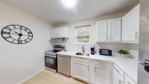 a white kitchen with a large clock on the wall at Furnished Garden Style Apt, Pool Gym Parking Pb in Newark