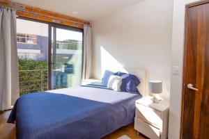 1 dormitorio con cama azul y ventana grande en ¡Nuevo! Bamboo & ROCK (WTC & City Views), en Ciudad de México
