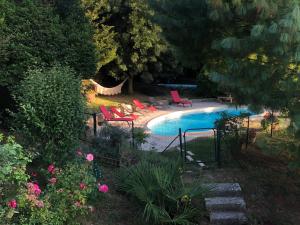a swimming pool with red chairs next to a yard at Gîte Au Coeur Du Pays Cathare in Fanjeaux
