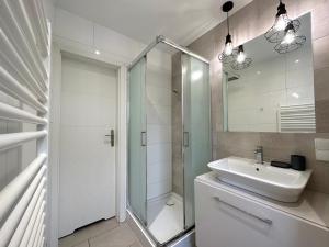 een witte badkamer met een wastafel en een douche bij MMRent Bubble Room in Gdańsk