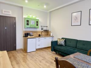 un soggiorno con un divano verde e una cucina di Starovka Apartament a Elblag Altre 13 foto