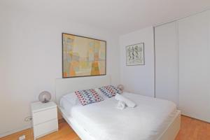 Apartment near Pigalle in Paris - Welkeys في باريس: غرفة نوم بيضاء مع سرير و لوحة على الحائط