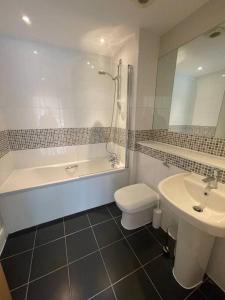 a bathroom with a tub and a toilet and a sink at Modern 2 Bed Apartment Next To Station + Parking in Beckenham