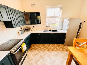 a kitchen with black cabinets and a wooden floor at Boutique rooms by Crosby beach in Crosby