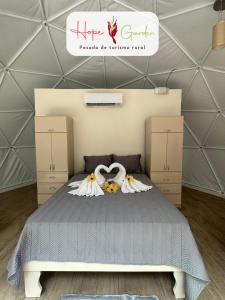 a bedroom with a bed with two swans on it at Glamping Hope Garden in Sarapiquí