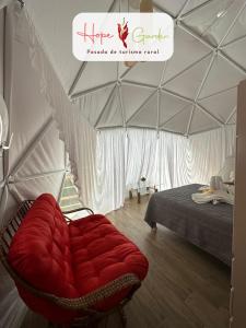 a red couch in a tent with a bed at Glamping Hope Garden in Sarapiquí