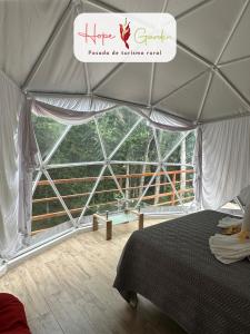 a tent with a bed and a large window at Glamping Hope Garden in Sarapiquí