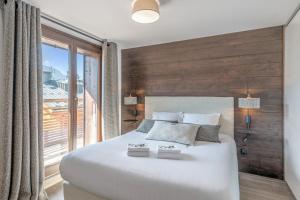 a bedroom with a large white bed with a large window at Beautiful T4 near the Megève ski lifts - Welkeys in Demi-Quartier