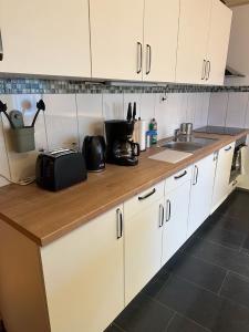a kitchen with white cabinets and a wooden counter top at bee Apartment: Ideal für Gruppen & Monteure in Lahnau +1 photo