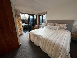 a bedroom with a large bed and a sliding glass door at Woolshed 17 - Self Catering Accommodation in Havelock North