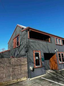 a gray building with a wooden door and a fence at Woolshed 17 - Self Catering Accommodation in Havelock North