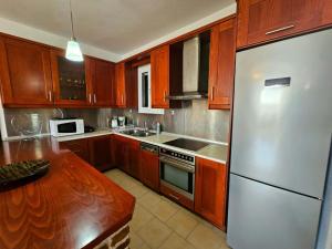 uma cozinha com armários de madeira e um frigorífico de aço inoxidável em Corfu Glyfada Beach Apartment 59 em Glyfada