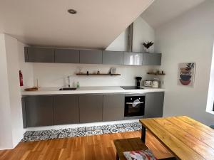 a kitchen with gray cabinets and a wooden table at Luxury Townhouse, Manchester Sleeps 6 in Manchester
