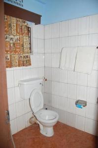 a bathroom with a white toilet in a tiled wall at Swahili House & Art in Arusha