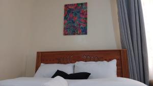 a painting above a bed with white sheets and pillows at Papino Studio Apartment in Nairobi