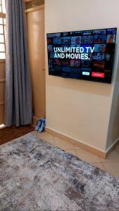 a living room with a television on a wall at Papino Studio Apartment in Nairobi