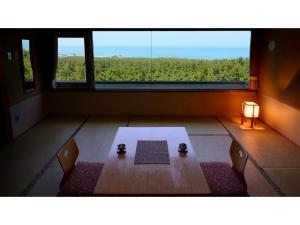um quarto com uma mesa e uma grande janela em Yunohama Onsen Hanayubi Nihonkai - Vacation STAY 67567v em Tsuruoka