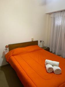 1 dormitorio con 1 cama naranja y 2 toallas en Nueva Hostería Rio Colorado Necochea en Necochea