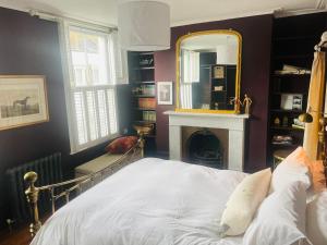 a bedroom with a bed with a mirror and a fireplace at Beautiful London Victorian house, sleeps 12 in London