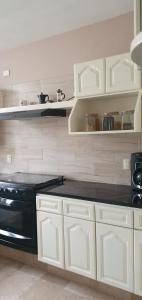 uma cozinha com armários brancos e um fogão preto em hermosa habitacion en casa residencial em Guadalajara