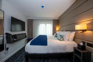 a hotel room with a large bed and a television at Signature London, The J Marylebone in London