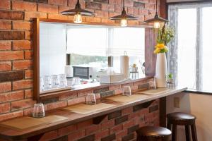 a brick wall with a mirror above a bar with stools at Wind Henza - Vacation STAY 73155v in Uruma