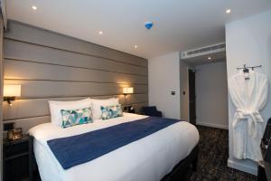 Signature London, The J Marylebone في لندن: غرفة فندق بسرير كبير ومخدات زرقاء وبيضاء