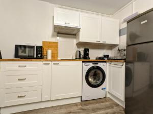 a kitchen with white cabinets and a washing machine at Appartement 4 personnes et jardin in Bielle