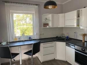 cocina con armarios blancos y encimera negra en Ferienhaus Albertus en Cottbus