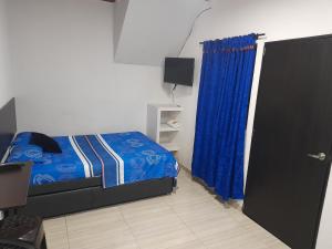 a bedroom with a bed and a blue curtain at apartaestudios el jardin 2 in Cali