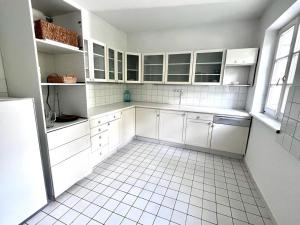 a kitchen with white cabinets and a white tiled floor at Green House bei Baden 