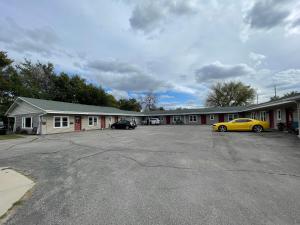 un bâtiment avec une voiture jaune garée sur un parking dans l'établissement The Village Motel, à Steamboat Rock