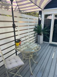 een tafel en stoelen op een veranda met een parasol bij Adorable 1 bedroom cottage in Forest Hills