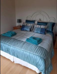 een groot bed met blauwe lakens en blauwe kussens bij The Lake House in Drumshanbo
