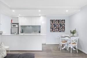 a white kitchen and dining room with a table and chairs at Royal Respite Spacious Apartment - Walk to Restaurants in Perth