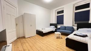 Cette chambre comprend deux lits et un canapé bleu. dans l'établissement Work&Stay - City nah, à Neumünster