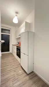 La cuisine est équipée de placards blancs et d'un réfrigérateur blanc. dans l'établissement Work&Stay - City nah, à Neumünster