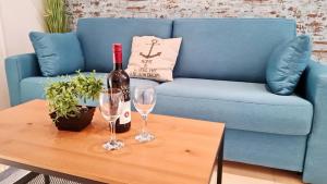 a blue couch with a bottle of wine and two glasses on a table at Apartments Epulon in Pula