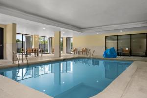 a swimming pool in a hotel with tables and chairs at Courtyard Indianapolis Northwest in Indianapolis