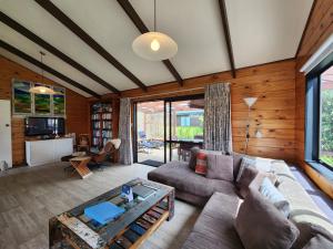 a living room with a couch and a table at Kotare Cottage Hahei in Hahei