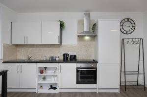 a kitchen with white cabinets and a stove top oven at King Sized Luxury - Stylish Studio Flat in Blackpool